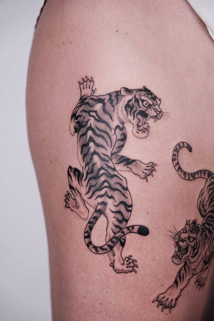Roaring blackwork tiger thigh tattoo in bold lines, done at a Hanoi tattoo studio specializing in custom Asian-inspired ink.