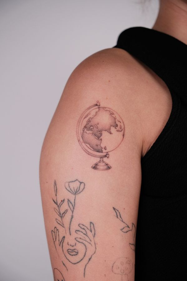 Minimalist globe tattoo on skin, fine line style, done at 3 Of Spades Tattoo Hanoi