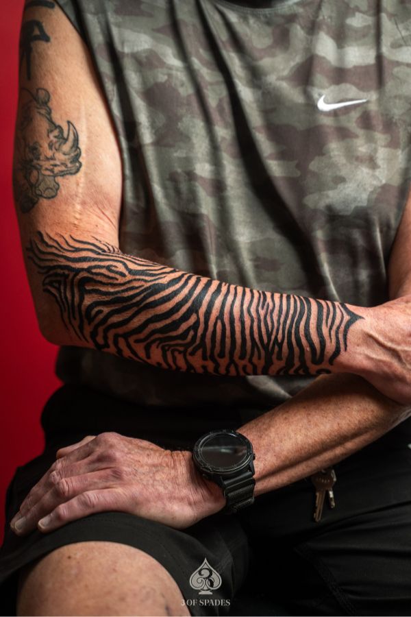 Bold zebra stripe blackwork tattoo covering the full forearm – created at 3 Of Spades Tattoo Studio in Hanoi.