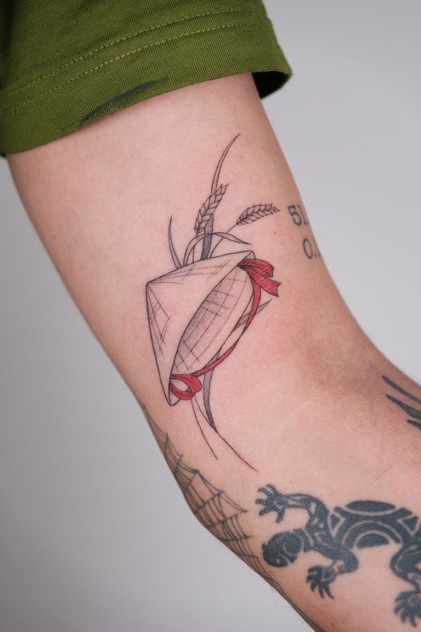 Vietnamese conical hat (nón lá) tattoo with red ribbon and rice detail – tattoo Hanoi
