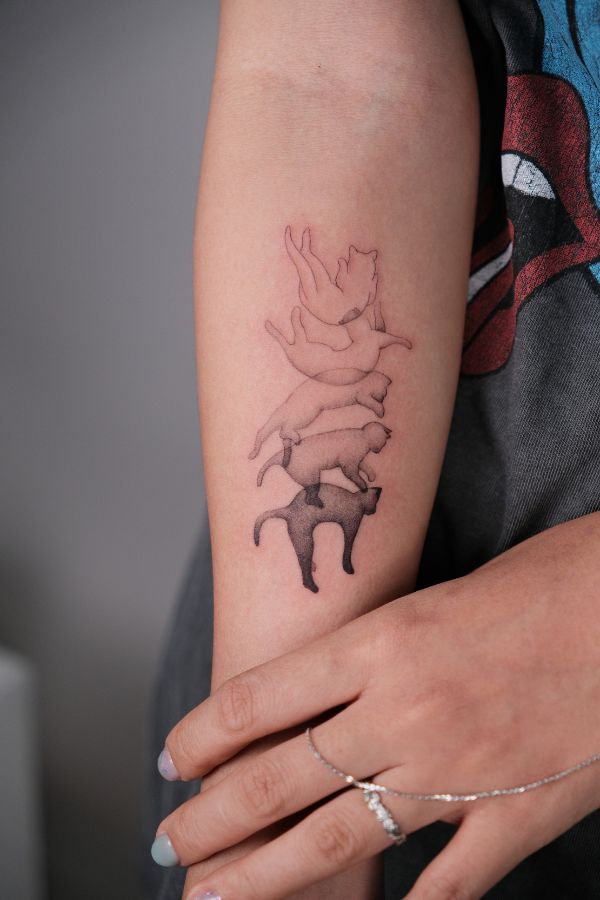 Minimalist tattoo of a cat in five positions of falling, transitioning from linework to solid black.