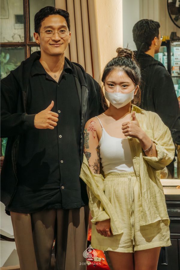 Tattoo artist and female customer posing with thumbs up after a successful tattoo session at 3 Of Spades Tattoo Studio in Hanoi.