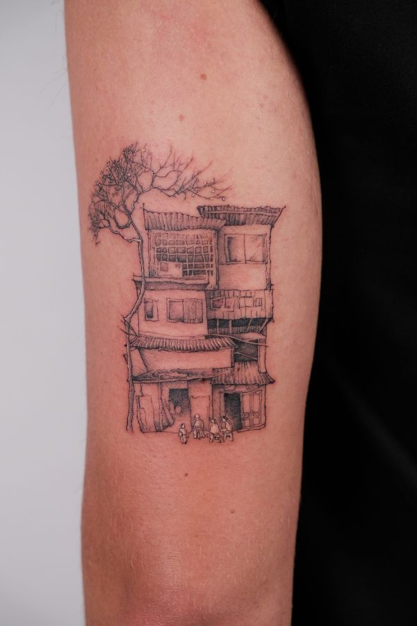 Fineline tattoo of an old Hanoi tube house with a leafless tree and people sitting in front.