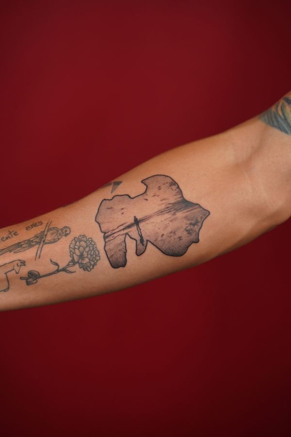 Tattoo of Africa-shaped silhouette with a detailed sunset landscape on the inner arm – done at 3 Of Spades Tattoo Studio in Hanoi.