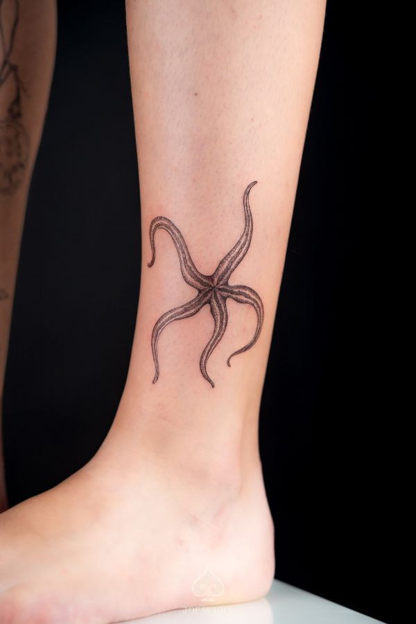 Realistic starfish tattoo on ankle in fine line style with natural flow and ocean-inspired detail.