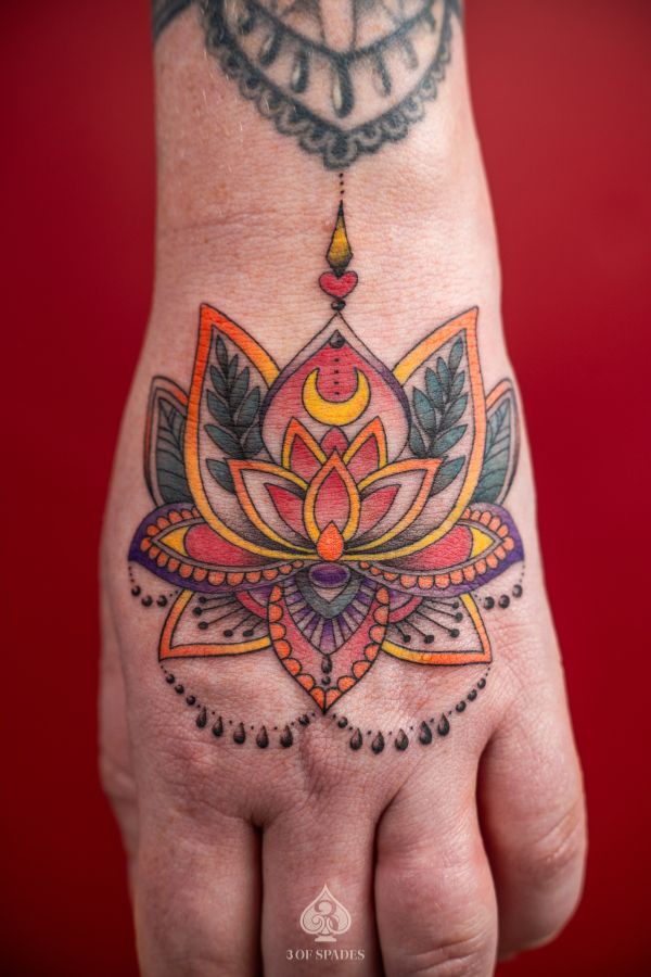 Close-up of a vibrant lotus mandala tattoo on the back of the hand with ornamental details and color blending – created at 3 Of Spades Tattoo Studio in Hanoi.