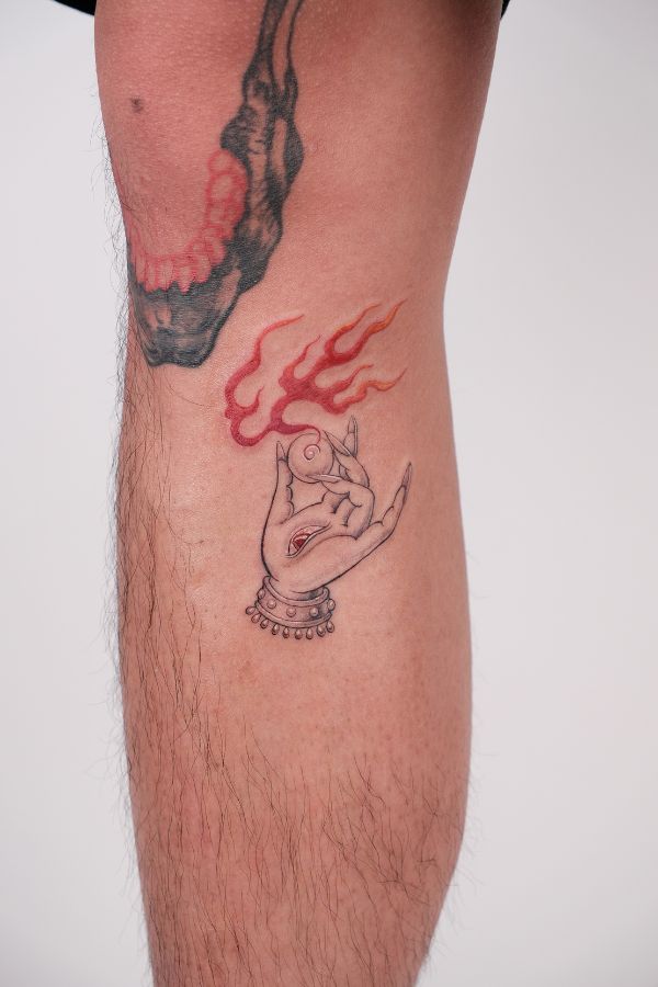 Fineline tattoo of symbolic hand holding pearl with fire flame, eye in palm, red accents – done at 3 Of Spades Tattoo Hanoi.