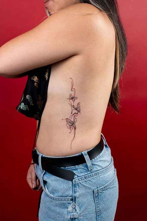 Fine Line Red Butterflies Tattoo featuring delicate red butterfly outlines, elegant wing details, and minimalist linework at 3 of Spades Hanoi Tattoo.