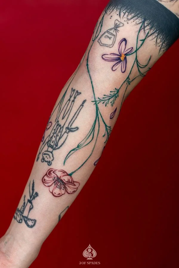 Growing Color Flower Arm Tattoo concept featuring colorful blooming flowers, delicate green stems, botanical leaves, and a natural upward-growing composition at 3 of Spades Hanoi Tattoo.