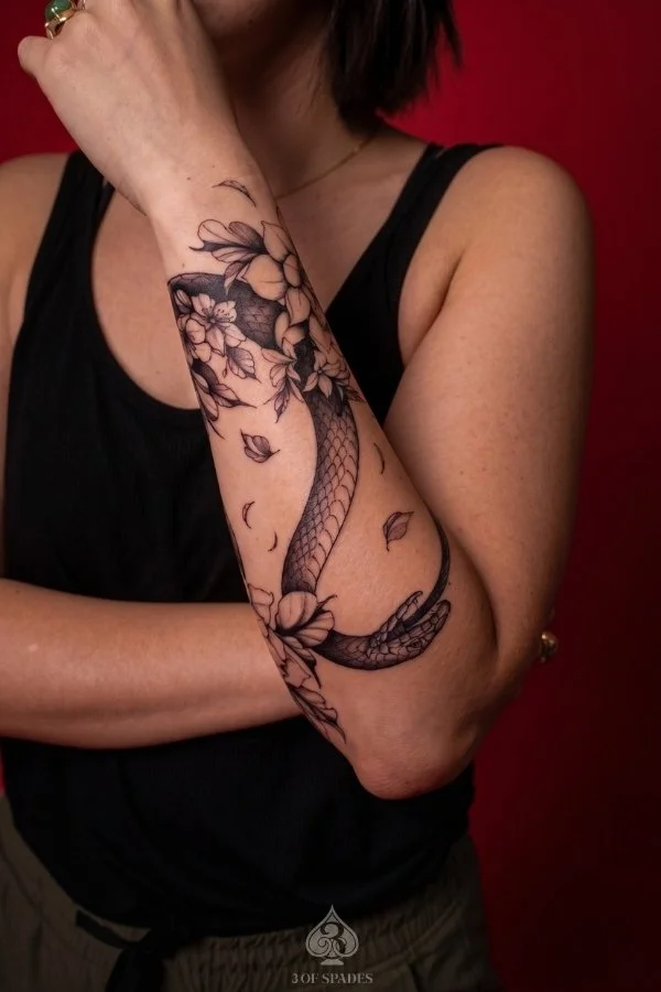 Snake wrapped around flowers arm tattoo