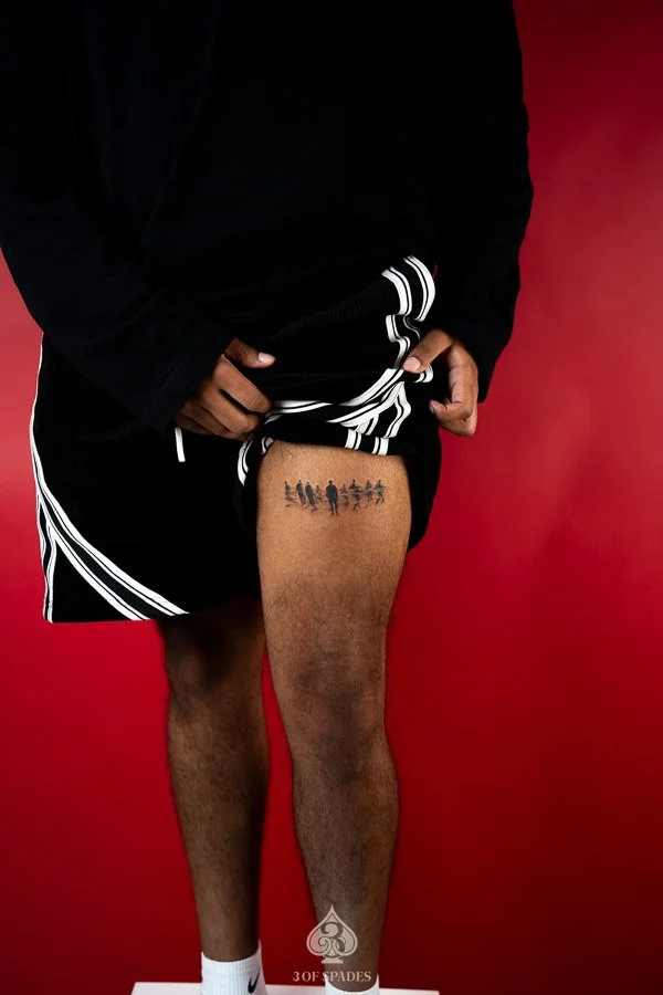 Sonder People Thigh Tattoo concept featuring miniature walking human silhouettes, scattered figures, and soft grey shadows in a minimalist black and grey composition.