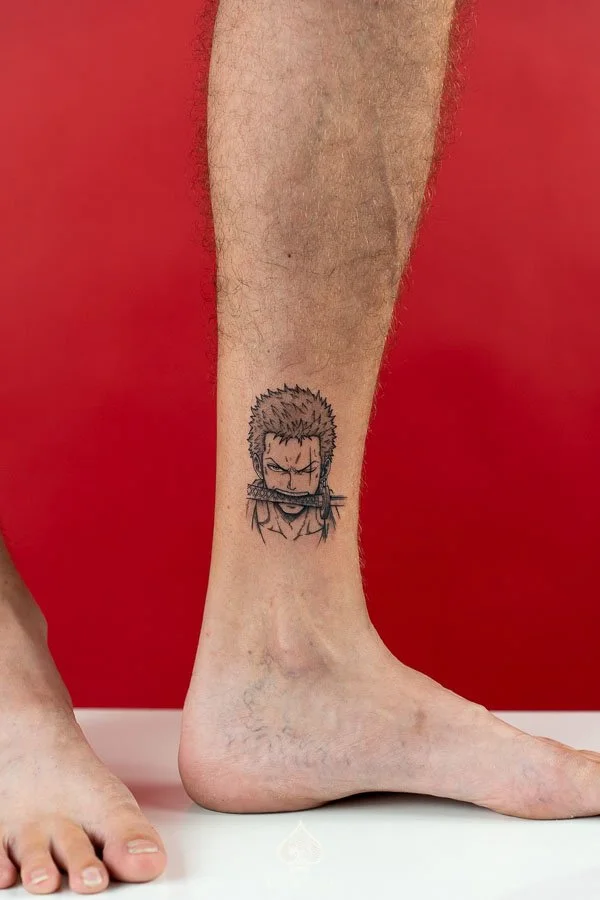 Illustrative Zoro Tattoo by Raven featuring Roronoa Zoro holding a sword in his mouth in a manga inspired design at 3 of Spades Hanoi Tattoo.