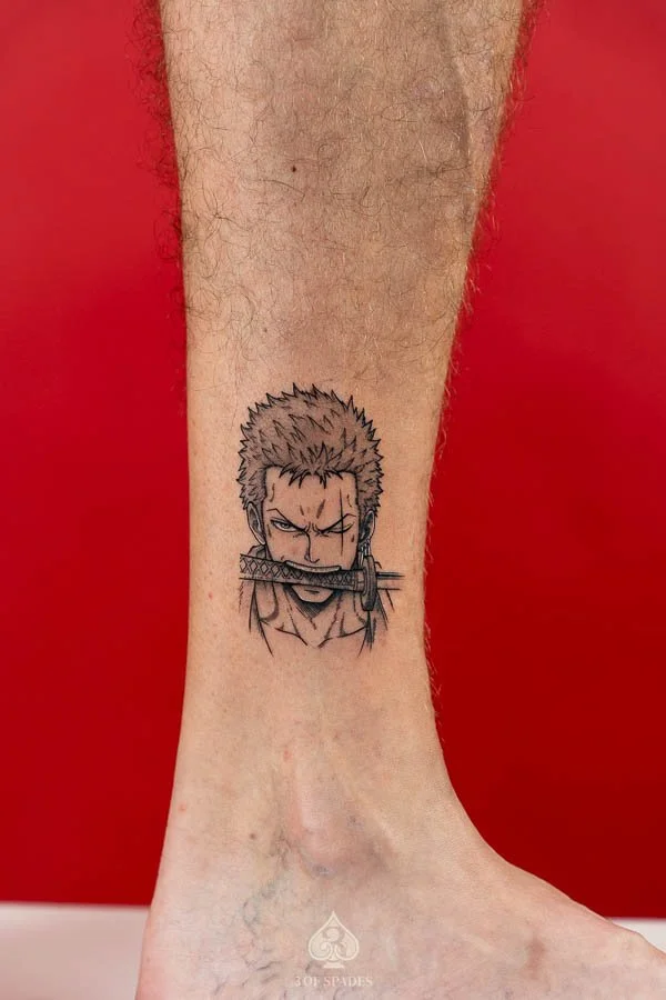 Illustrative Zoro Tattoo by Raven featuring Roronoa Zoro holding a sword in his mouth in a manga inspired design at 3 of Spades Hanoi Tattoo.
