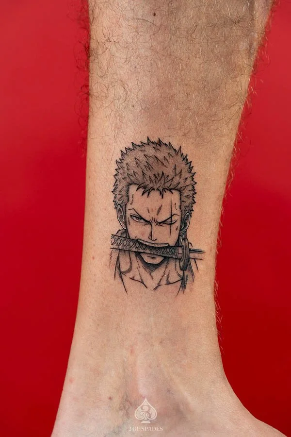 Illustrative Zoro Tattoo by Raven featuring Roronoa Zoro holding a sword in his mouth in a manga inspired design at 3 of Spades Hanoi Tattoo.