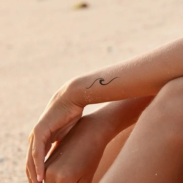 women waves wrist tattoo